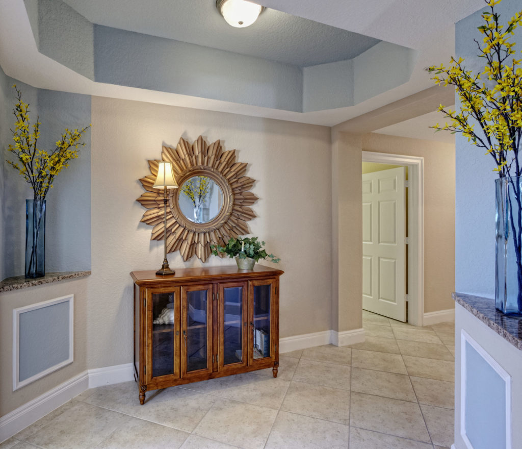 Condominium Interior, a hallway with display cabinet and sunburst style mirror, vases and flowers.